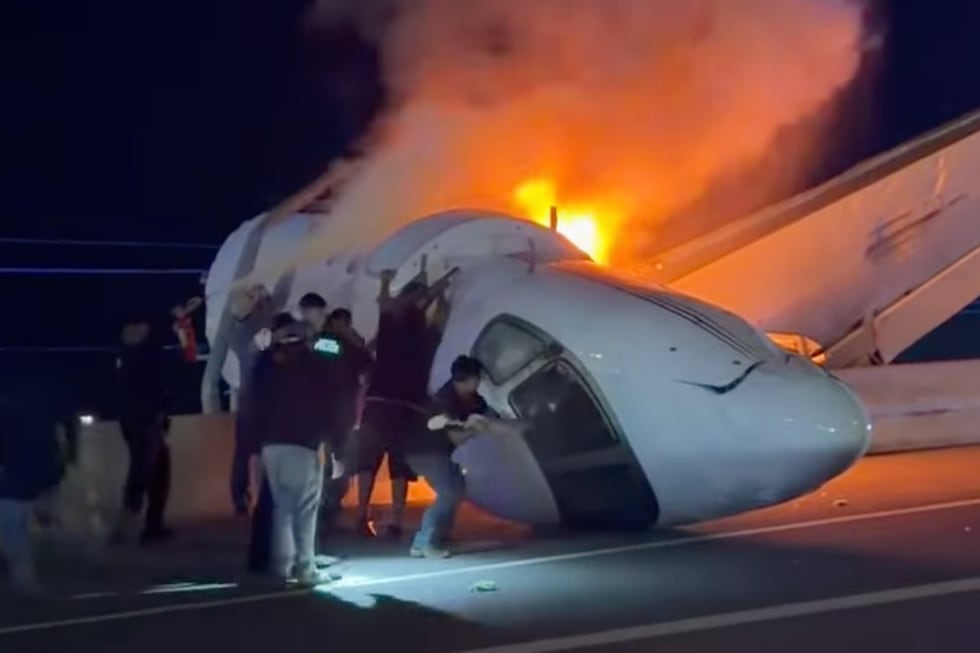 People attempt to pull passengers out of a plane after it crashed on a highway Tuesday, June...